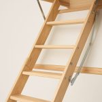Close-up of a wooden loft ladder with visible rungs and foldable mechanism against a neutral background